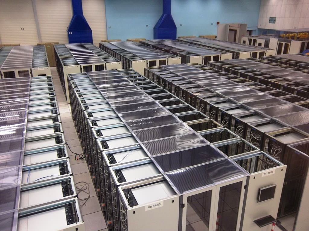 Filas de racks vistas desde arriba con cubiertas plásticas de confinamiento y conductos azules de refrigeración