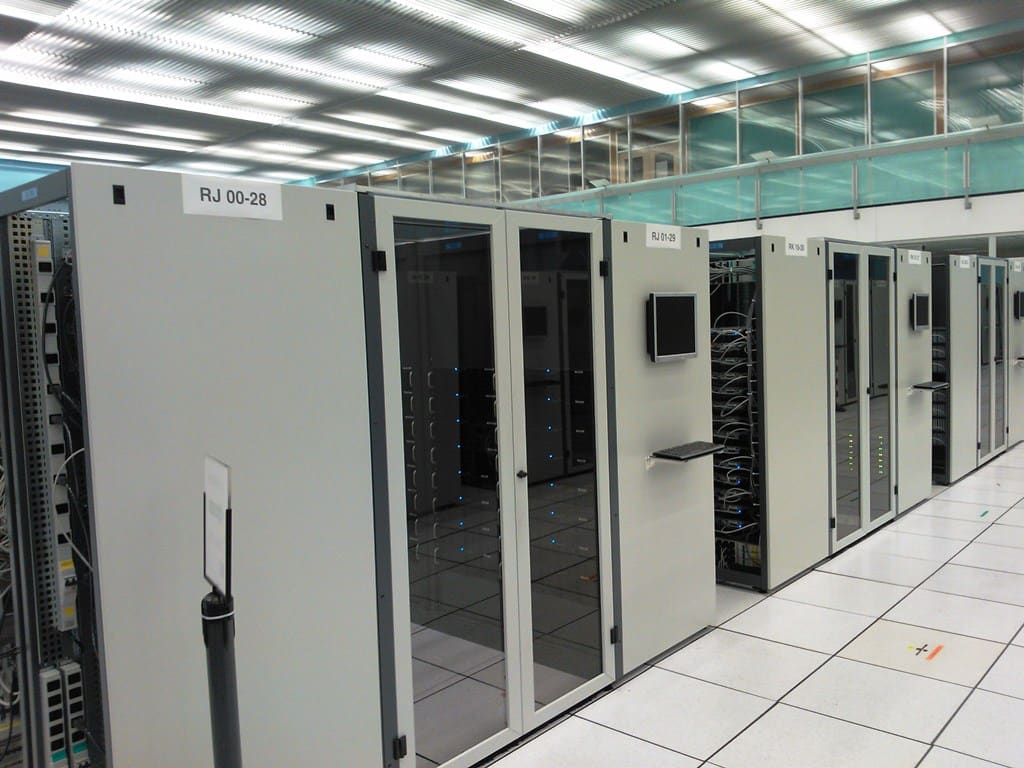 Cabinas de rack cerradas con puertas de cristal, monitor plano en la puerta y etiquetas RJ 00-28 y RJ 01-29.