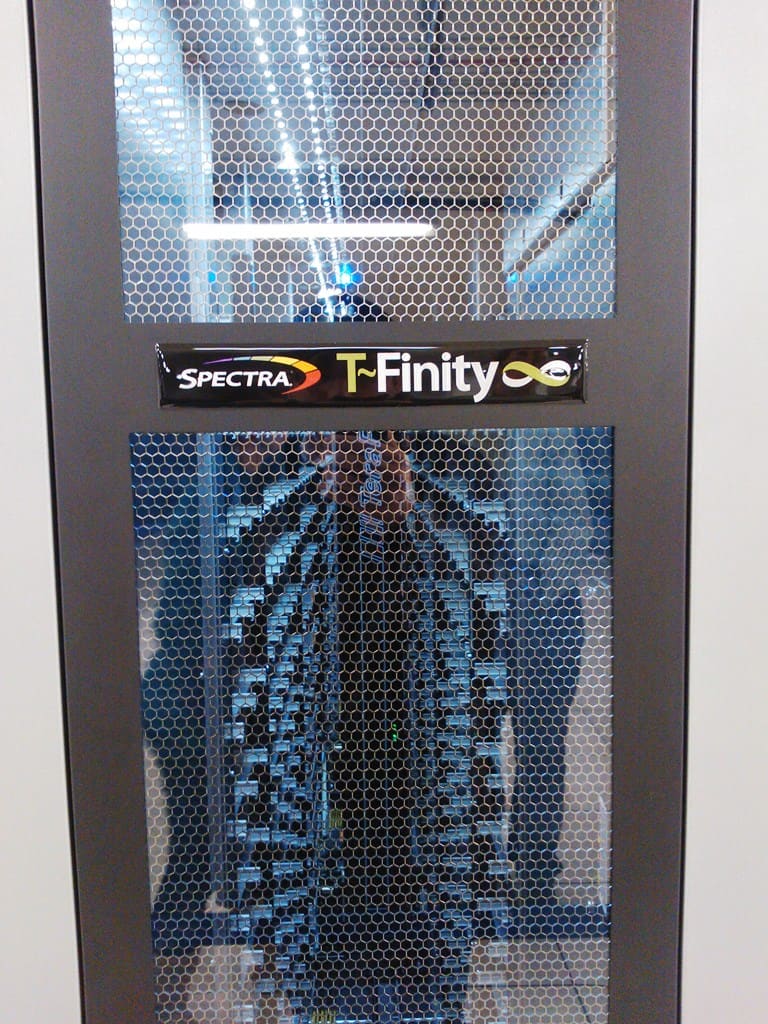 Puerta de malla hexagonal de una biblioteca de cintas Spectra Logic T-Finity con los cargadores al fondo