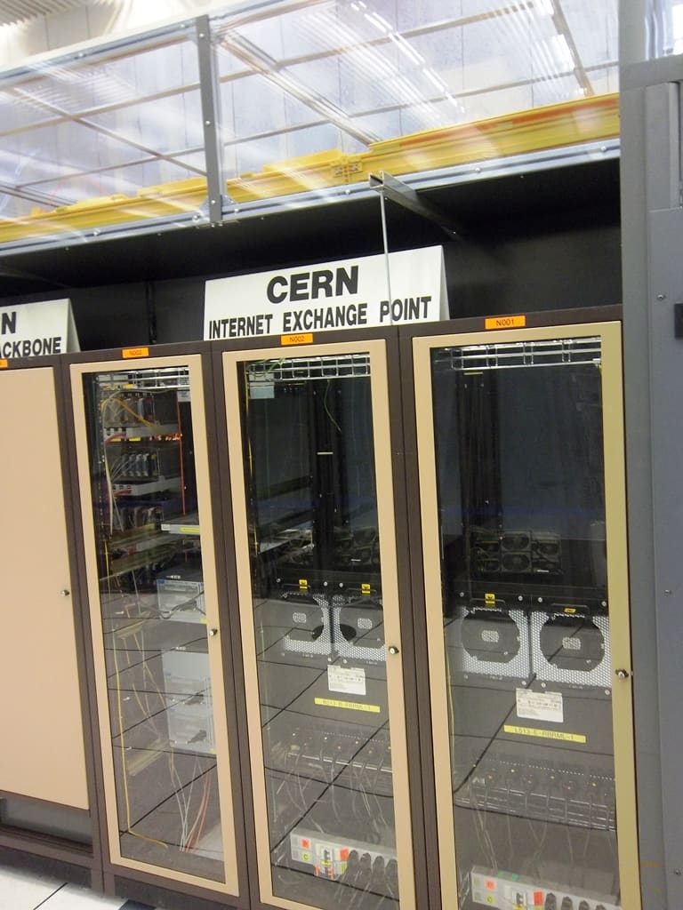 Racks tras puertas de cristal rotuladas 'CERN Internet Exchange Point' y 'Backbone', con routers y ventiladores