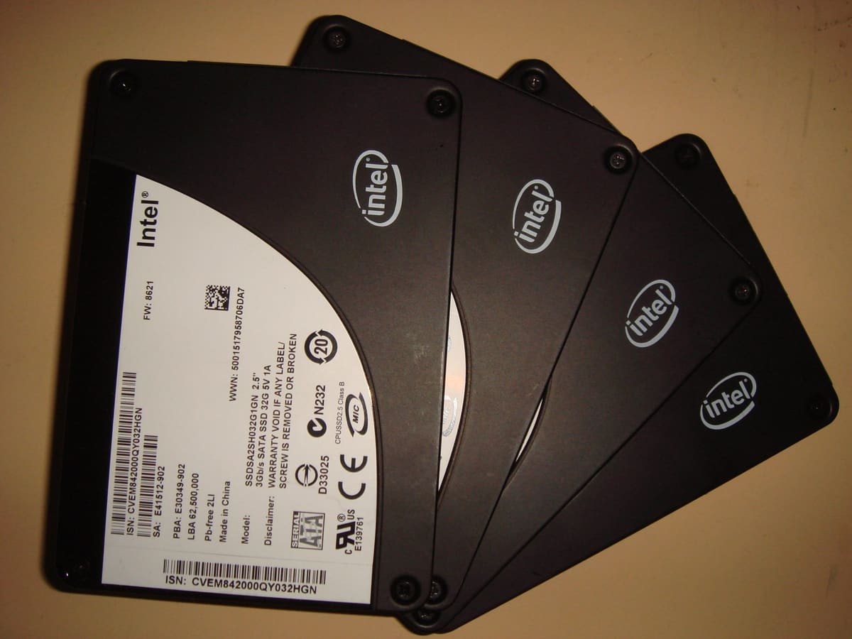 Cuatro SSD Intel abiertos en abanico, mostrando la etiqueta de modelo del primero y el logo Intel del resto.