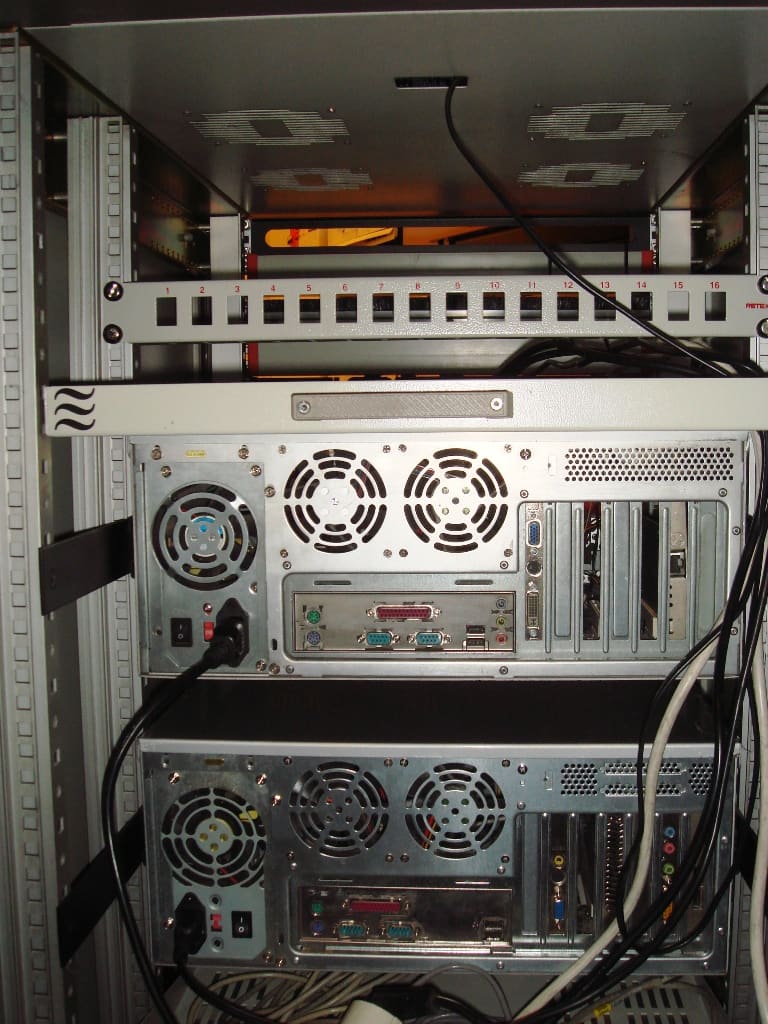 Trasera del rack: panel de conexiones del 1 al 16 y dos servidores con sus fuentes, ventiladores y puertos VGA y serie