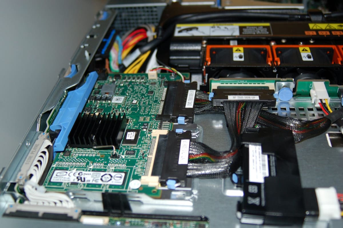 Controladora RAID con disipador y zocalo DIMM junto al cable SAS del backplane y los ventiladores del chasis