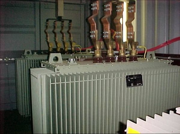 Transformador eléctrico de potencia con embarrados de cobre y aisladores en la parte superior