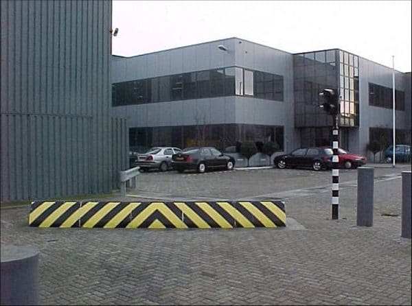 Exterior del edificio del centro de datos con barrera vial a rayas amarillas y negras y coches aparcados