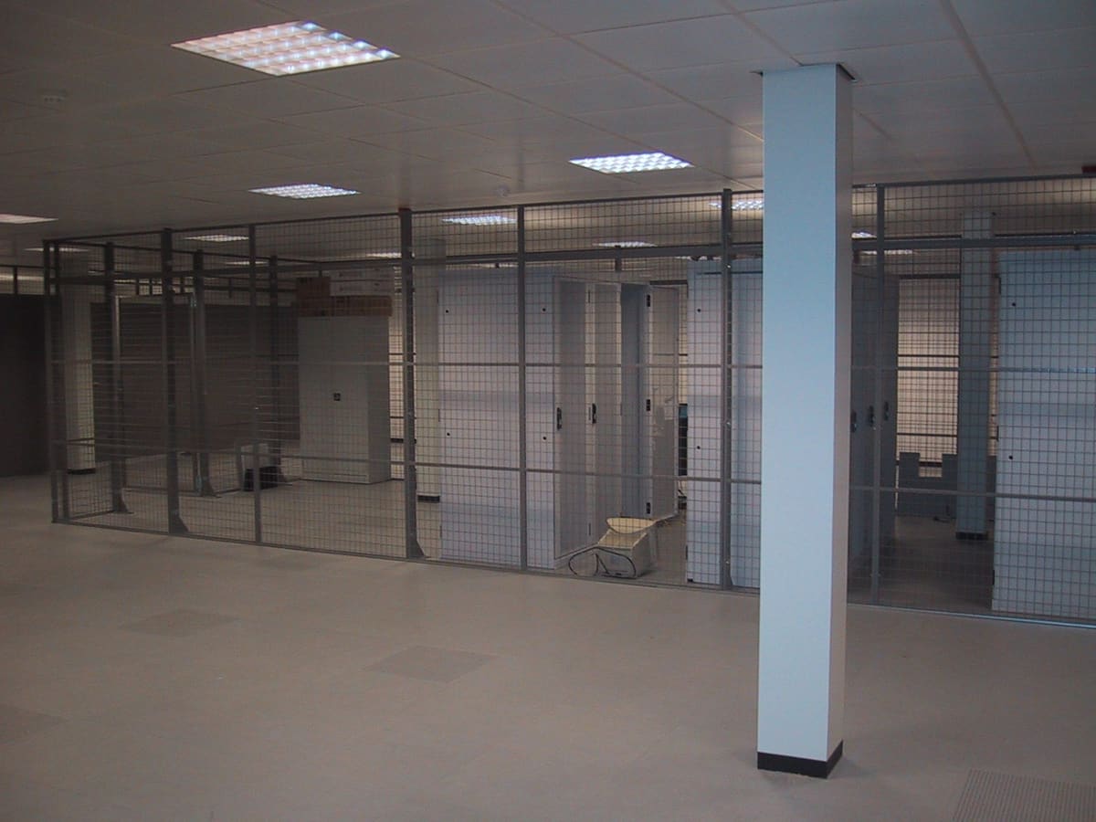 Sala de CPD vacía con jaulas metálicas de malla separando áreas antes de instalar los racks