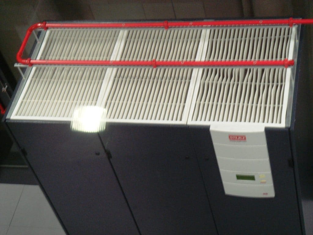 Unidad de climatización de precisión Stulz con rejillas de filtro y tubería roja contra incendios en el CPD