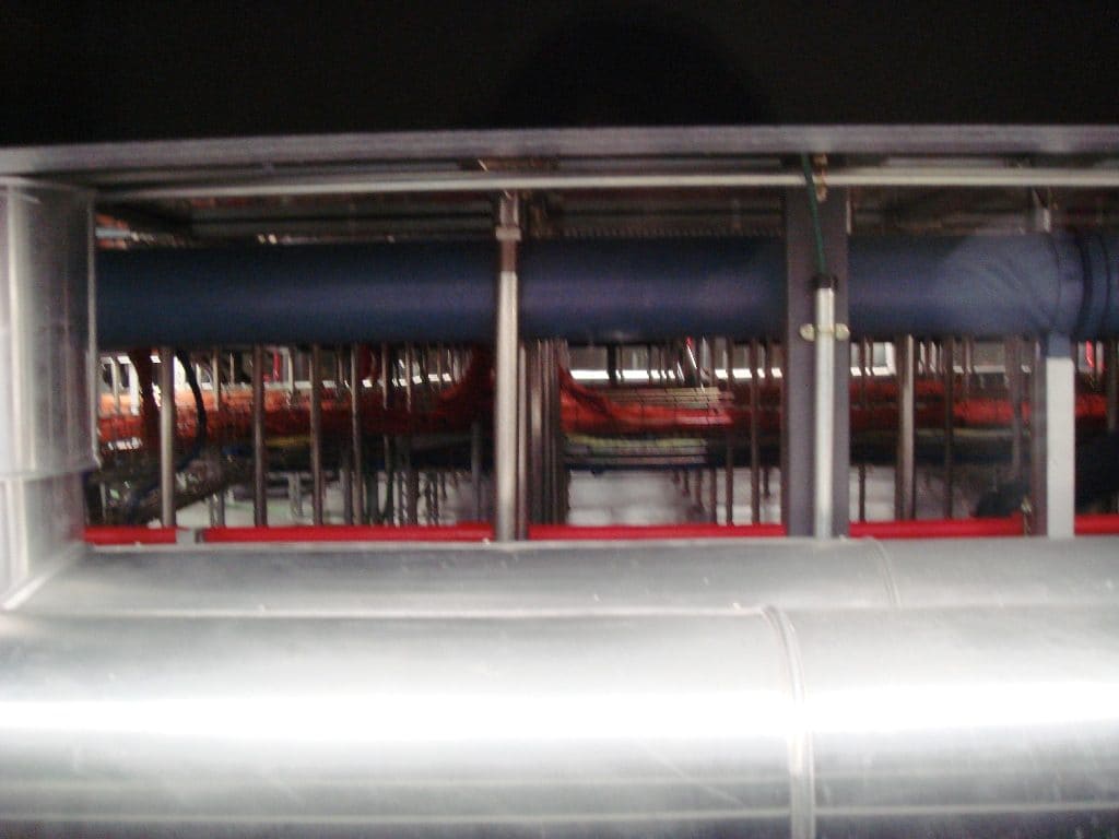 Detalle de conductos de refrigeración y tuberías bajo el suelo técnico elevado del centro de datos